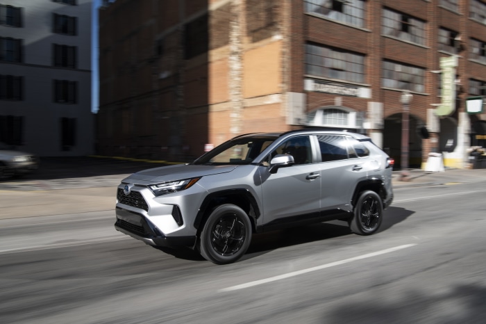 Silver Toyota RAV4 SE Hybrid driving on city street