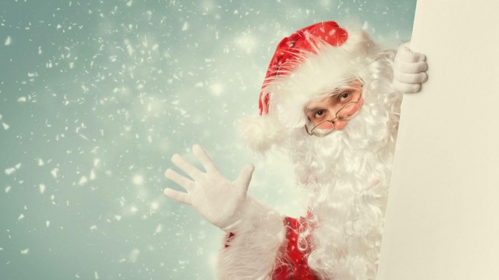 Santa Claus waving behind a blank sign
