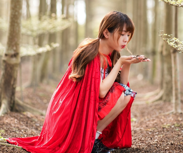 Asian girl dressed as Red Riding Hood in forest