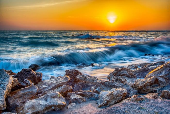 Ocean waves crashing on rocks at sunset