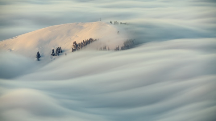 Snowy mountain peak emerging from fog