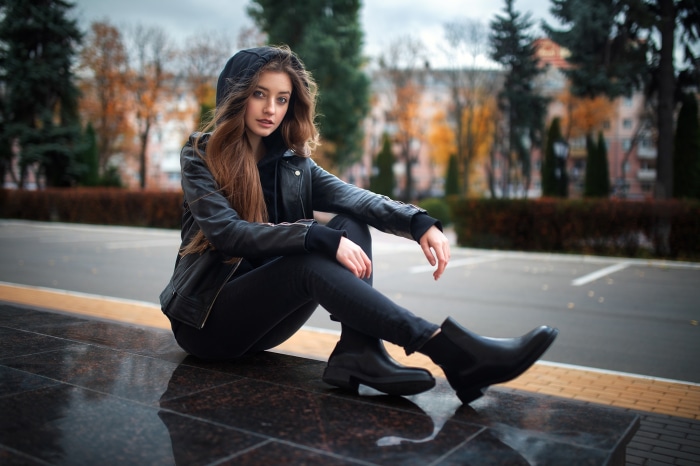 Woman in leather jacket sitting outdoors