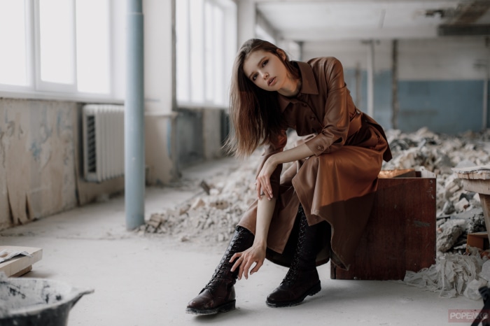 Model in brown coat and boots in abandoned building