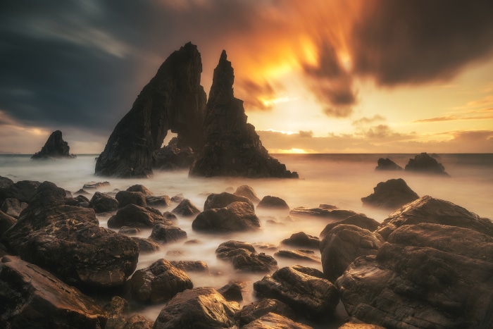 Rocky coastline with sea arch at sunset