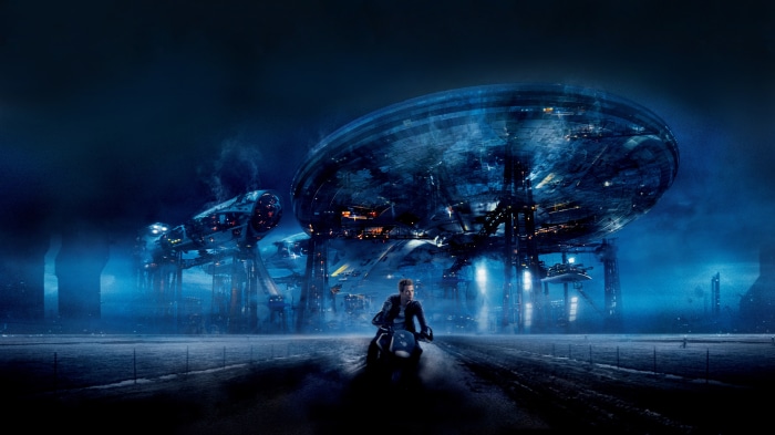 Man on motorcycle in front of alien ships