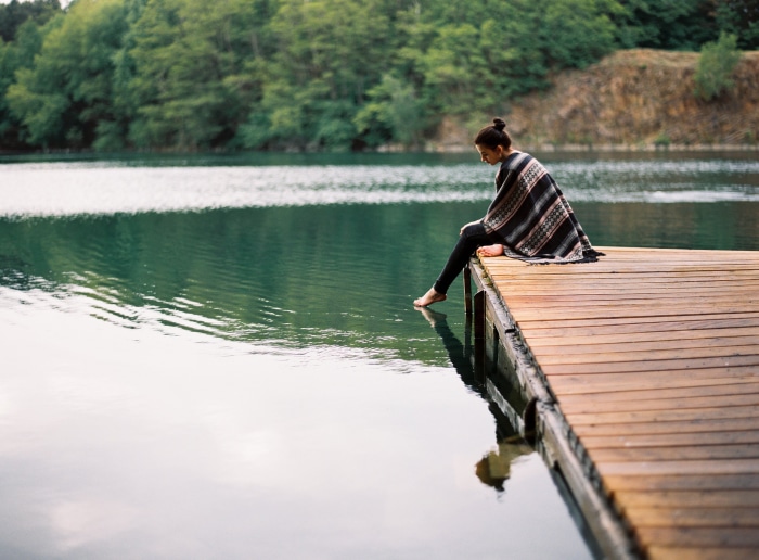 Woman sitting on a wooden pier by a lake