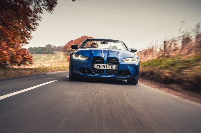 Blue BMW M4 Competition Convertible driving on a road