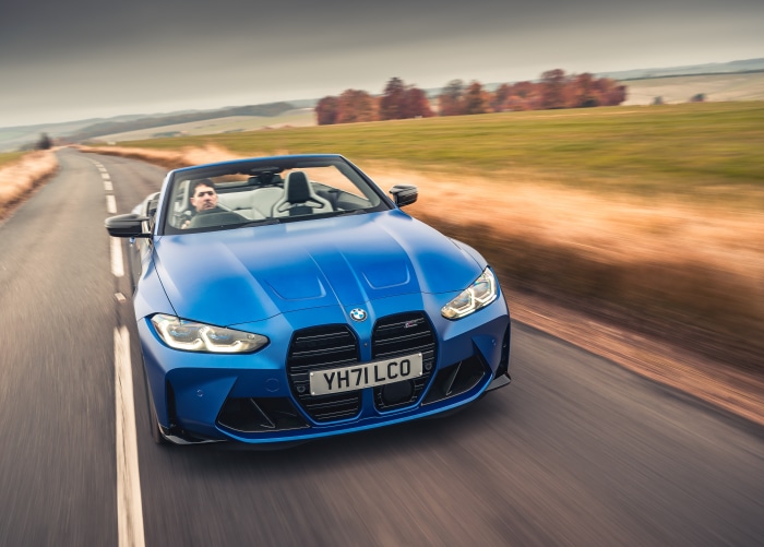 Blue BMW M4 Competition Convertible driving on a road