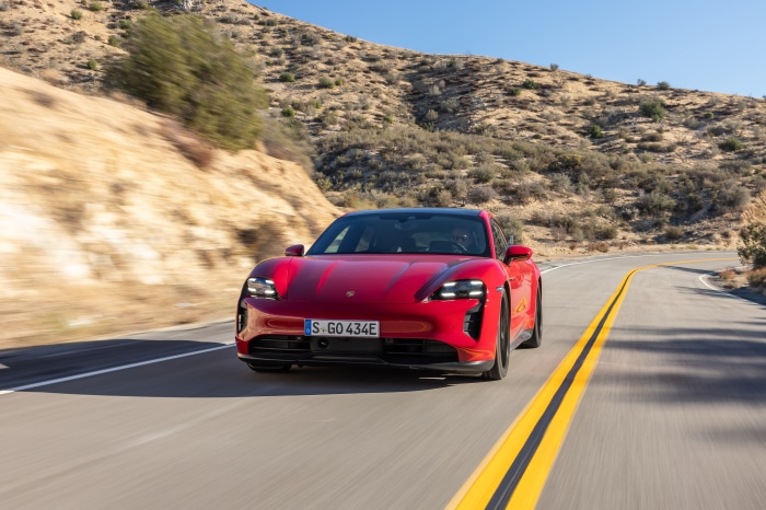Red Porsche Taycan GTS Sport Turismo driving on a road