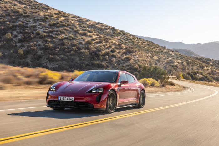 Red Porsche Taycan GTS Sport Turismo driving on a winding road