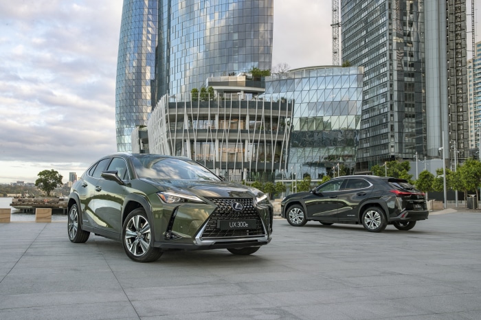 Two Lexus UX 300e SUVs parked in front of modern buildings
