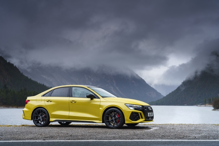 Yellow Audi RS3 Sedan parked by a lake with mountains