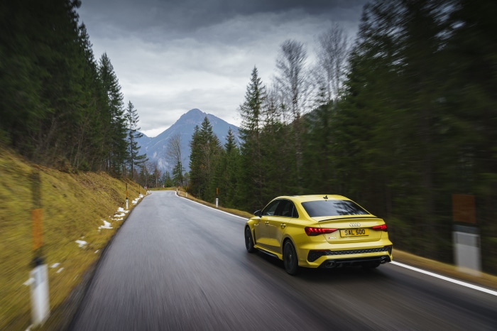 Yellow Audi RS3 Sedan driving on a mountain road