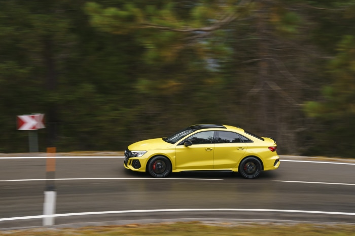 Yellow Audi RS3 Sedan driving on a wet road