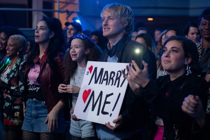 Owen Wilson and others holding Marry Me sign