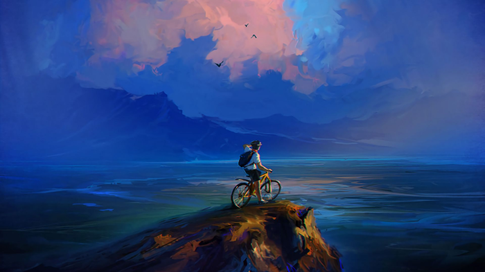 Cyclist on a cliff overlooking a vast landscape at dusk