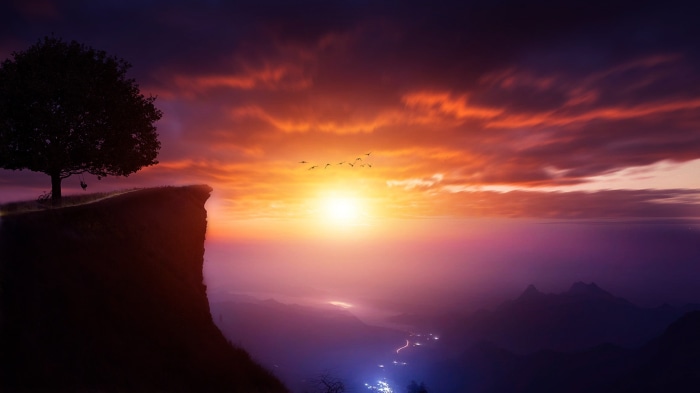 Sunset over mountains with a tree on a cliff