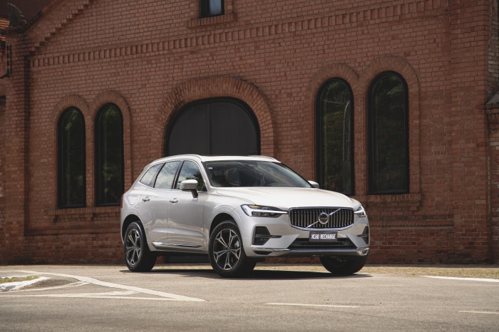 White Volvo XC60 Recharge SUV parked in front of brick building