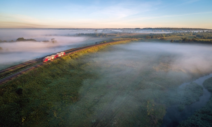 Train traveling through foggy Russian landscape at sunrise