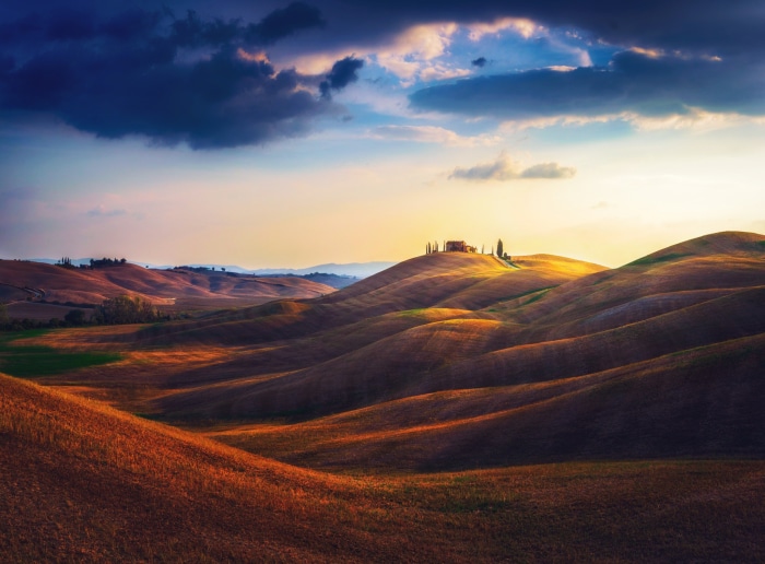 Tuscany landscape with rolling hills and a farmhouse at sunset