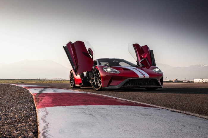 Red Ford GT supercar with doors open on a racetrack