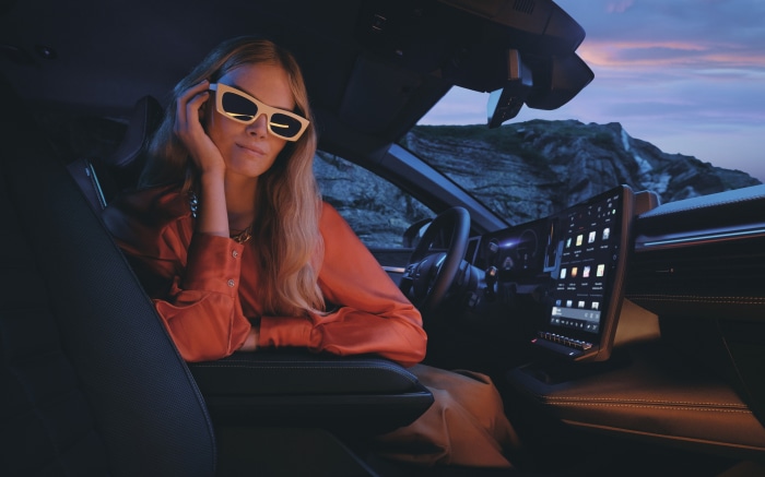 Woman in sunglasses inside a car at dusk