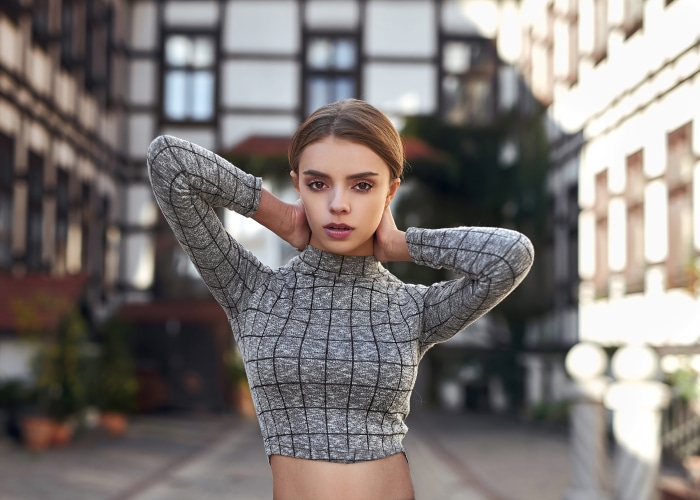 Woman with hands behind head in front of buildings