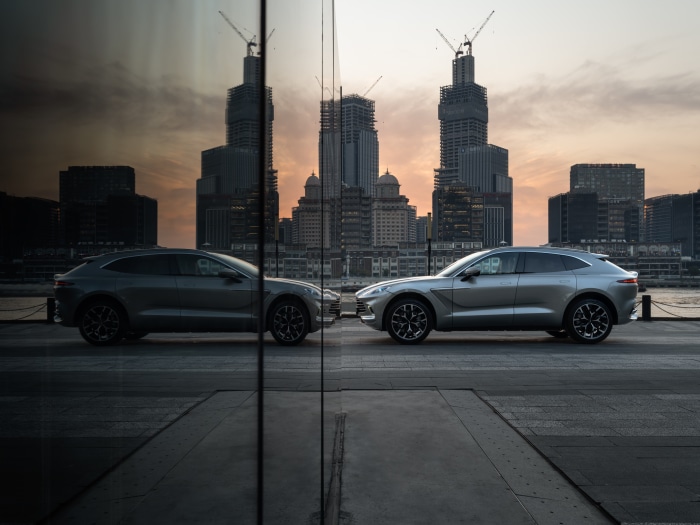Aston Martin DBX cars reflected in glass with city skyline