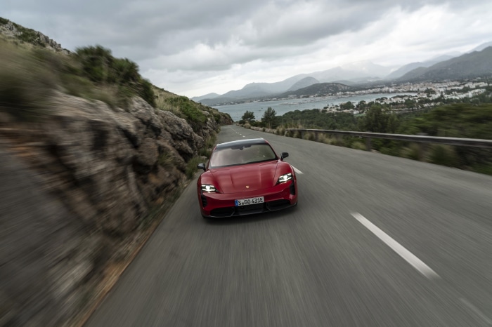 Red Porsche Taycan driving on a coastal road