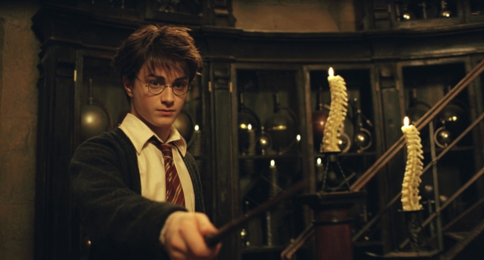 Harry Potter holding a wand in a dark room
