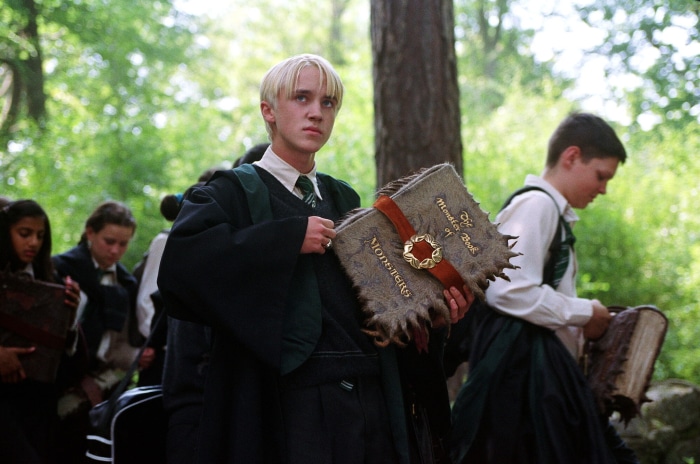 Draco Malfoy from Harry Potter holding The Monster Book of Monsters
