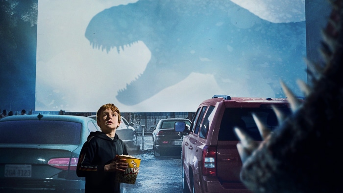 Boy at drive-in movie with Tyrannosaurus Rex projection