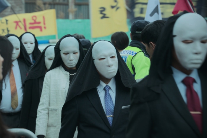 People in white masks and black robes in Hellbound