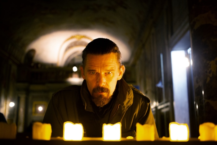 Ethan Hawke in a dimly lit room with candles