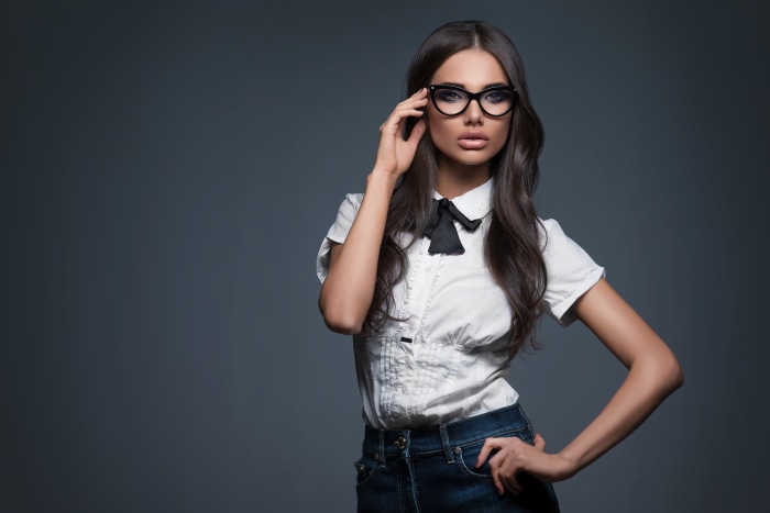 Woman with black hair and glasses wearing a white shirt