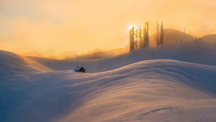 Winter landscape with a small cabin at sunrise