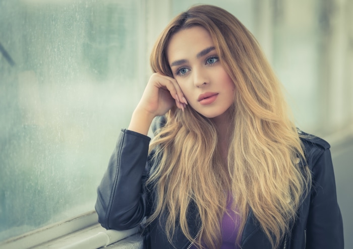 Young woman with blonde hair looking out a window