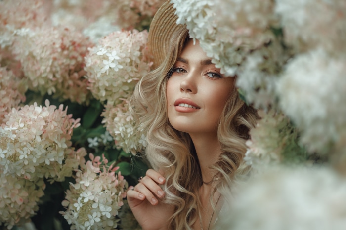 Woman in straw hat among hydrangeas
