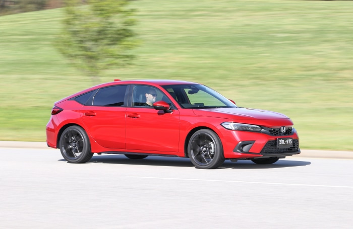 Red Honda Civic Hatchback driving on a road