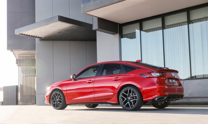 Red Honda Civic Hatchback parked near a modern building