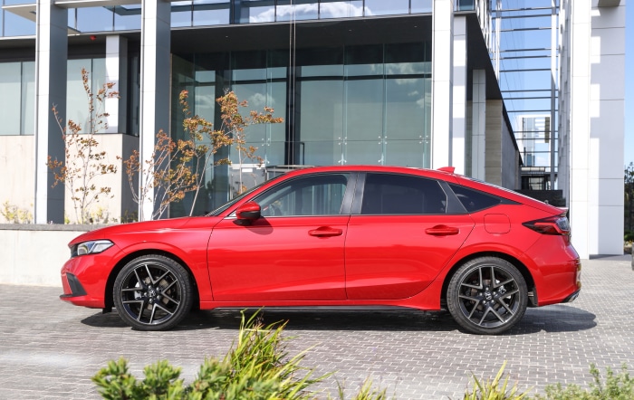 Red Honda Civic Hatchback parked in front of a modern building