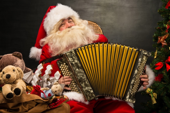 Santa Claus playing accordion with Christmas tree