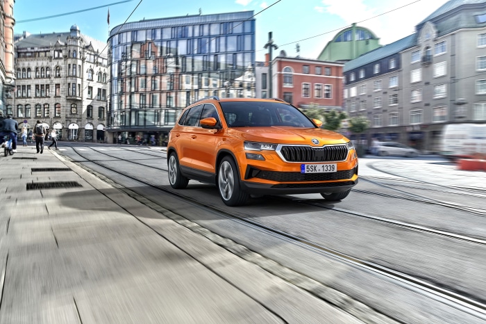 Orange Škoda Karoq SUV driving on city street