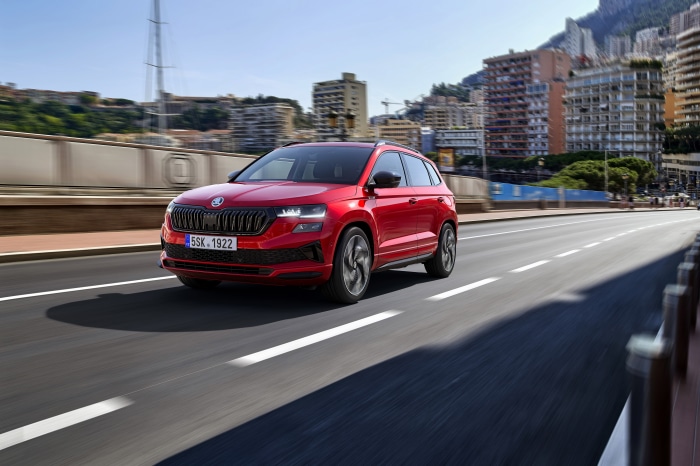 Red Škoda Karoq Sportline SUV driving on a city road