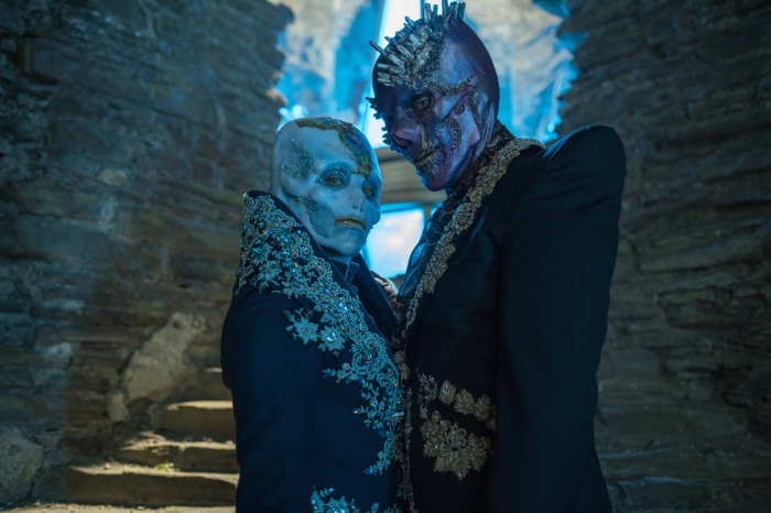 Two figures with elaborate masks and costumes in Doctor Who