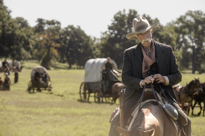 Sam Elliott on horseback with wagons in the background