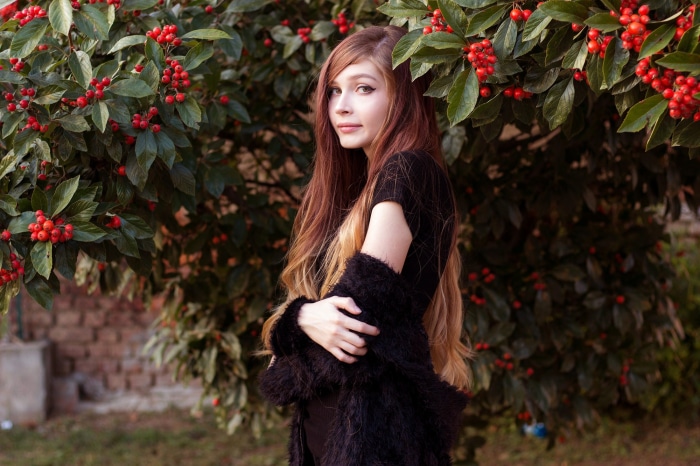 Woman in black dress and fur coat near red berries