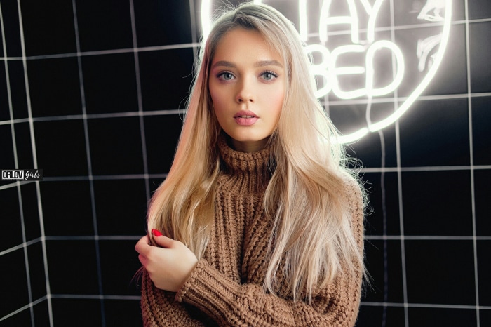 Young woman with blonde hair wearing a brown sweater