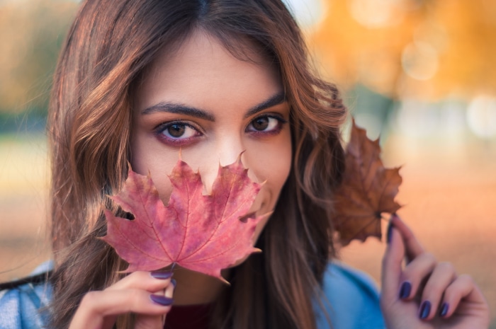 Woman with brown eyes holding autumn leaves