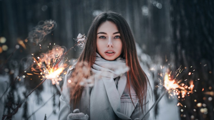 Brunette woman holding sparklers in winter